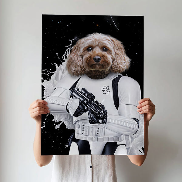 A person holds a Star Wars Stormtrooper custom pet portrait poster featuring a dog’s head in stormtrooper armor with a paw print logo, set against a space-themed background. The persons face is hidden behind the artwork.