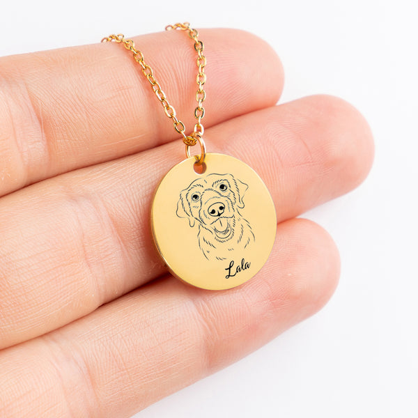 A hand holds the Dog Portrait Necklace - Coin Necklace, a gold circular pendant engraved with a dogs face and the name Lola—an ideal personalized pet jewelry piece and thoughtful gift for pet lovers.