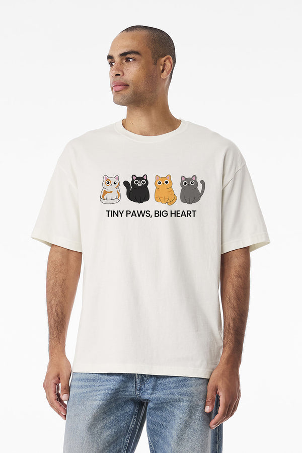 A man wears the “Tiny Paws, Big Heart” vintage pet t-shirt with four cartoon hamsters and playful text, standing against a plain white background—an ideal gift or keepsake for any pet lover.