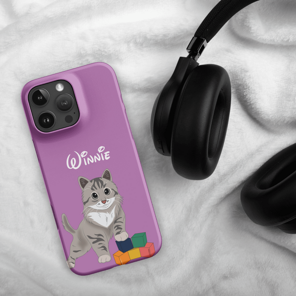 The Custom Pet iPhone Case – Disney features a purple cover with an illustrated gray cat, colorful blocks, and the name Winnie beside black headphones on a white, fluffy fabric background.