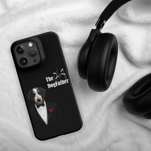 A Custom Pet iPhone Case – The Dogfather, featuring a dog in a tuxedo and text The DogFather, is displayed next to black headphones on a soft white surface.