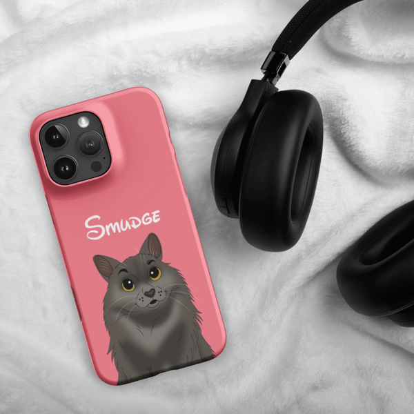 A Custom Pet iPhone Case – Disney, in pink with a cartoon gray cat and Smudge text, lies beside black over-ear headphones on soft white fabric.