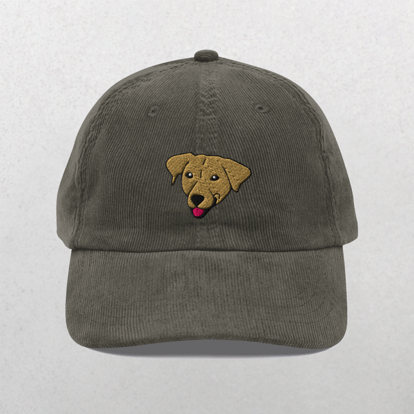 The Custom Pet Portrait Corduroy Cap in grey features an embroidered brown dogs face with its tongue out. This personalized pet hat makes a unique pet keepsake or gift. Shown on a plain, light background.