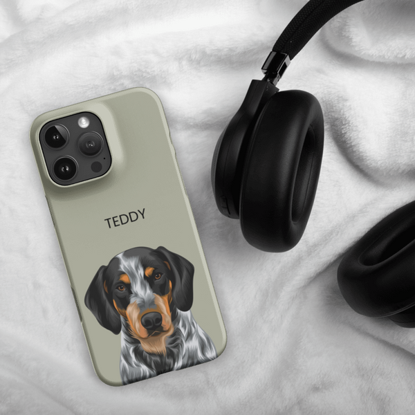 A Custom Pet iPhone Case – Modern Vector Art with an illustrated dog and the name TEDDY sits beside black headphones on a soft, white, fluffy surface.