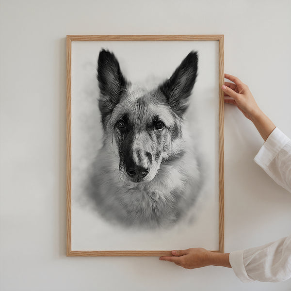 A person in a white long-sleeve shirt holds The Pencil Sketch Art, a framed black and white personalized German Shepherd dog canvas, against a plain white wall.