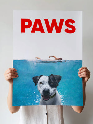A person holds the Paws Film Cover: a playful poster featuring a swimmer above and a happy dog underwater, mimicking the Jaws movie poster. PAWS stands bold in red—a unique, personalized canvas for any pet lover.