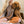 A smiling woman with long blonde hair hugs a brown poodle while wearing the “Dogs are my Favorite People” T-shirt, featuring cartoon dog illustrations—a fun pet tee for any animal lover.