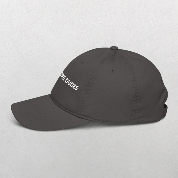 A Classic Organic Dad Cap - Dogs Before Dudes in black, featuring white MORE DUDES embroidery on the side, shown against a plain light gray background.