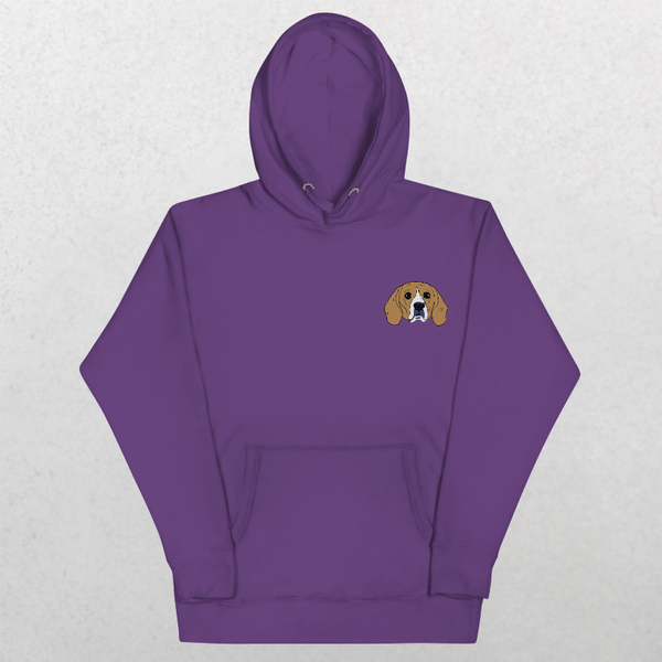 The Embroidered Custom Pet Hoodie in purple features a small cartoon beagle face embroidered on the left chest, shown on a light textured background—ideal as a personalized gift for dog lovers.