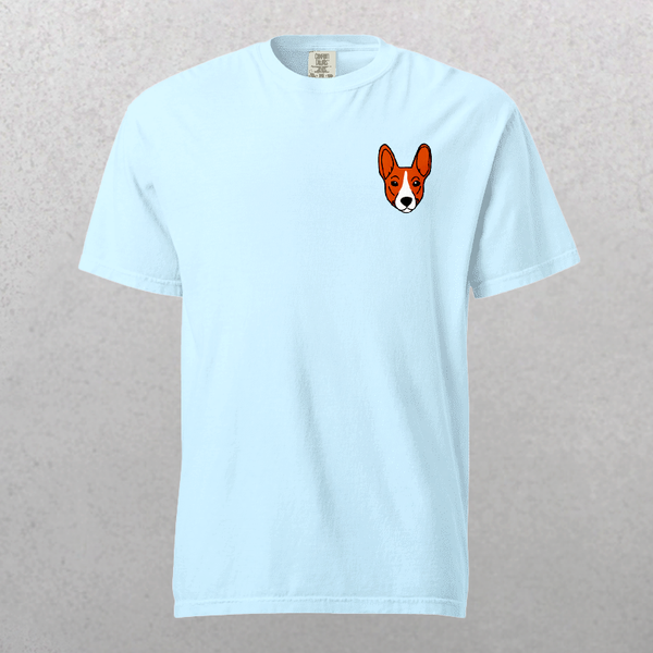 The Embroidered Pet Portrait Organic T-Shirt in Sky Blue features a small corgi face on the upper left chest—an ideal cute gift for pet lovers, shown against a neutral textured background.