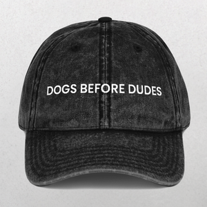 The Vintage Cap - Dogs Before Dudes is a black hat featuring the slogan DOGS BEFORE DUDES embroidered in white—an ideal, funny accessory for any dog mom.