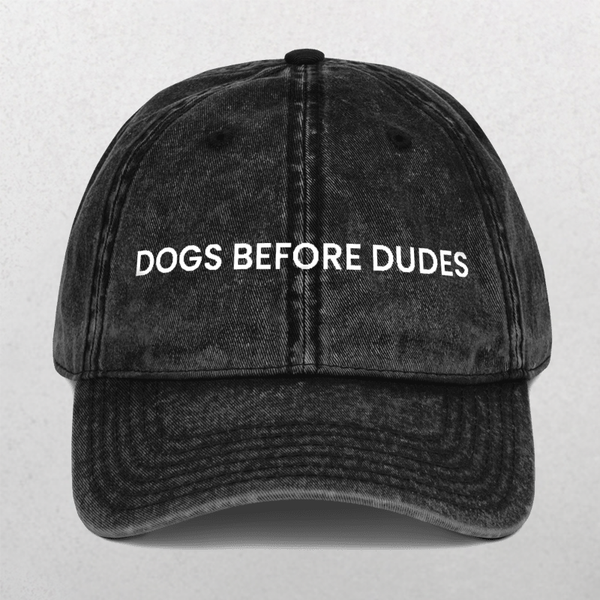 The Vintage Cap - Dogs Before Dudes is a black hat featuring the slogan DOGS BEFORE DUDES embroidered in white—an ideal, funny accessory for any dog mom.