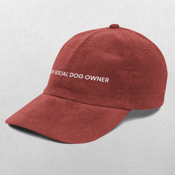 The Chord Vintage Cap - Anti Social Dog Owner is a red corduroy baseball hat with white ANTI-SOCIAL DOG OWNER embroidery on the front, shown against a light grey background.