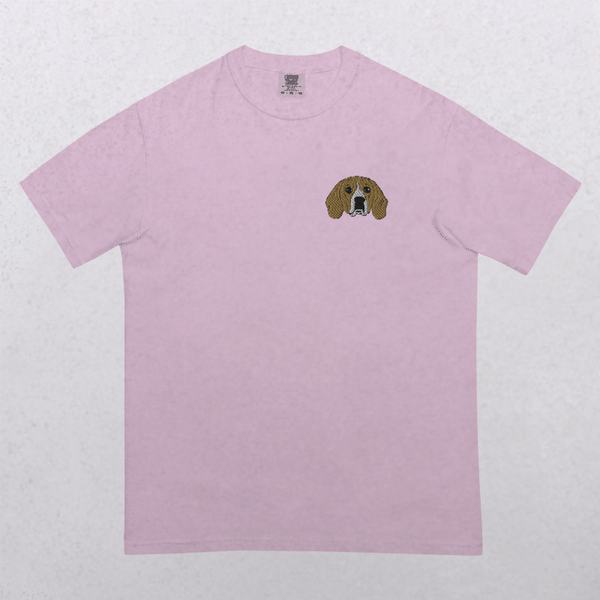 The Embroidered Pet Portrait Organic T-Shirt in light pink features a small brown and white dog face embroidered on the left chest, shown on a plain white background—a unique keepsake for dog lovers.