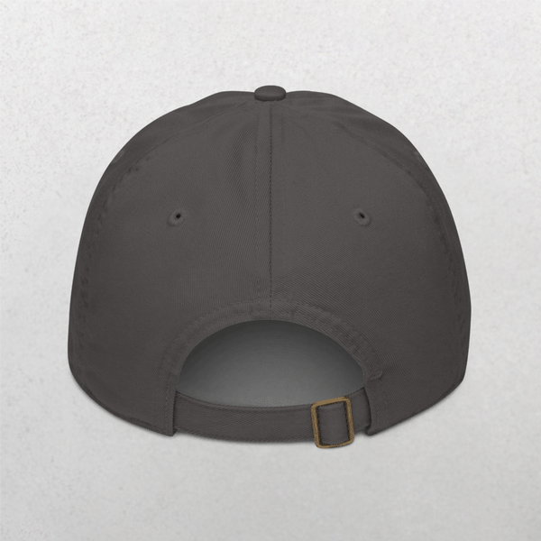 The Classic Organic Dad Cap - Dogs Before Dudes is shown from the back in dark gray, featuring a metal buckle strap and two side ventilation eyelets. Perfect for dog lovers, it rests on a light speckled background.