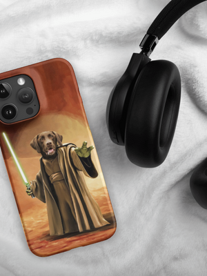A Custom Pet iPhone Case – Star Wars, showing a dog as a Jedi with a green lightsaber, is placed beside black headphones on white fabric.