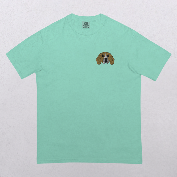 The Embroidered Pet Portrait Organic T-Shirt features a light green color and a small embroidered dog face with floppy brown ears on the left chest, making it a unique keepsake for animal lovers.