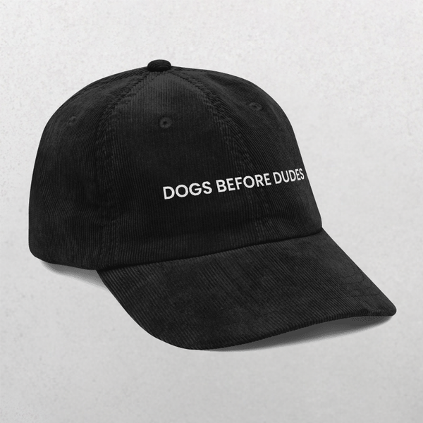 The Chord Vintage Cap - Dogs Before Dudes is a black baseball cap with DOGS BEFORE DUDES in bold white letters, ideal for any dog mom hat collection. Shown against a light gray background, it’s perfect for trendy dog lovers.