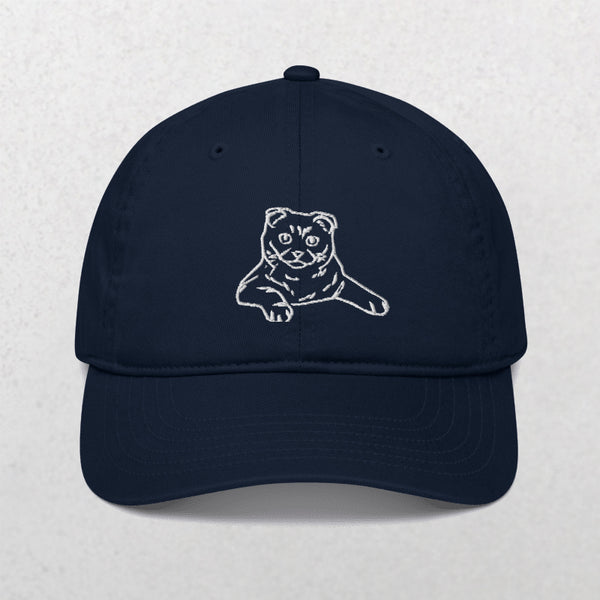 The Embroidered Line art Pet Portrait Organic Classic Dad Cap is a dark navy blue hat featuring a white outline of a folded-ear cat with an extended paw—an ideal personalized pet gift for any cat lover.