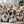 Several real corgis sit on a couch behind two Custom Shape Pet Pillows featuring close-up corgi faces. A plant and soft window light add to the cozy, cheerful atmosphere—making it a perfect pet keepsake for any animal lover.