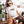 Relaxing on a cozy porch, a woman wears the Dogs are my Favorite People vintage pet t-shirt and pets her brown and white dog. Surrounded by plants and cushions, its a charming scene—an ideal gift for any pet lover.