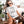 A woman with long hair and sunglasses relaxes on a porch, petting her brown and white dog while wearing the “Things I do in my spare time” t-shirt—a perfect gift for any pet lover.