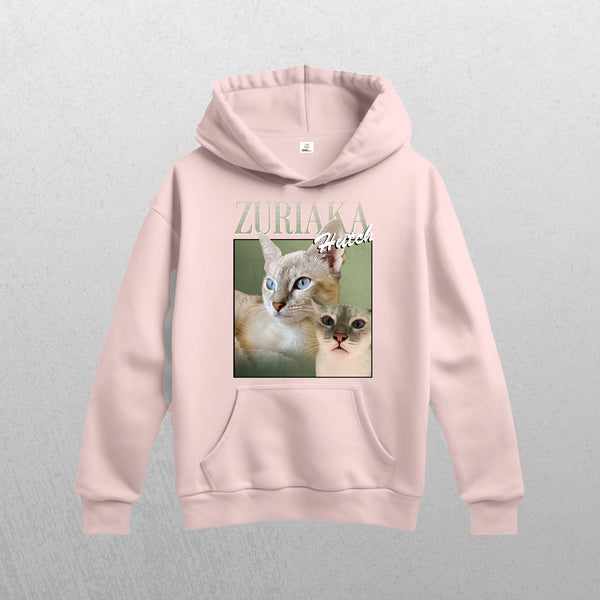 The light pink Personalised Homage Hoodie | Jungle features a graphic of two blue-eyed cats with ZURIAKA and Hutch above them in stylized fonts—a cozy, vintage-inspired keepsake for animal lovers.
