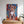 The Oil Masterpiece - Custom Pet Portrait features a vibrant painting of a brown and white puppy above a wooden dresser with potted plants in a sunlit, modern room—ideal as heartfelt pet memorial wall art.