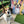 A brown and white dog sits on a patio beside the Abstract Masterpiece - Custom Pet Portrait, a colorful canvas featuring its likeness. Lush plants and green grass are visible in the background.