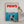 A person hangs the Paws Film Cover canvas—a playful artwork mimicking the Jaws poster, featuring a swimmer above and dog below with PAWS in bold red. This fun pet decor is a perfect gift for dog lovers.
