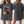A woman wears the Personalised Homage Tee | Cosmic, a loose dark gray vintage shirt featuring a colorful graphic of two pugs and REGGIE Brown; both front and back views of this unique pet keepsake shirt are shown.