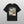 A black Personalised Homage Tee | Jungle, featuring two light-colored cats with blue eyes and ZURIAKA Hutchinson above them. The green background highlights the cats, and the shirt is displayed on a light gray surface.