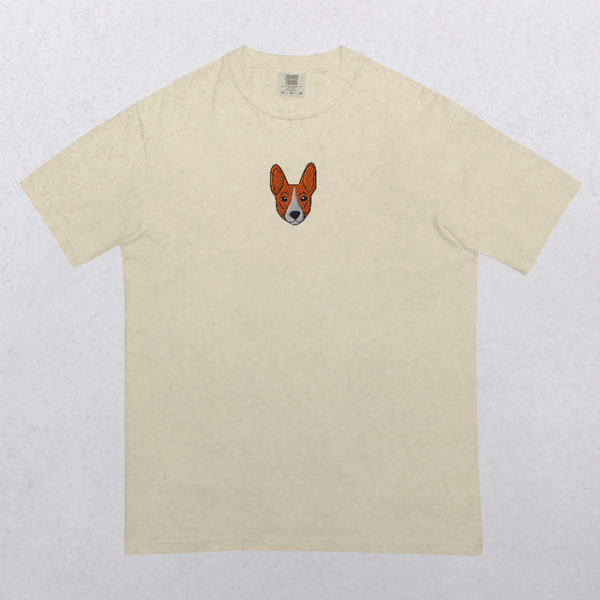 The Embroidered Pet Portrait Organic T-Shirt is a plain beige tee with a small, embroidered cartoon dog face—large ears and all—centered on the chest. A charming vintage style, it’s the perfect gift for pet lovers.