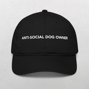The Classic Organic Dad Cap - Anti-Social Dog Owners is a black hat with the words ANTI-SOCIAL DOG OWNER in bold white letters on the front, standing out against a plain, light-colored background.