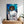 The Star Wars Princess Leia custom pet portrait features a cat dressed as Leia with a blaster against a starry backdrop. This colorful wall art, perfect for pet lovers, hangs above a dresser decorated with plants.