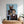 A framed portrait titled “Step Brothers” sits on a dresser, featuring a young man and his dog in matching argyle sweaters. This charming, softly lit artwork is the ideal gift for pet lovers, adding cozy decor to any space.
